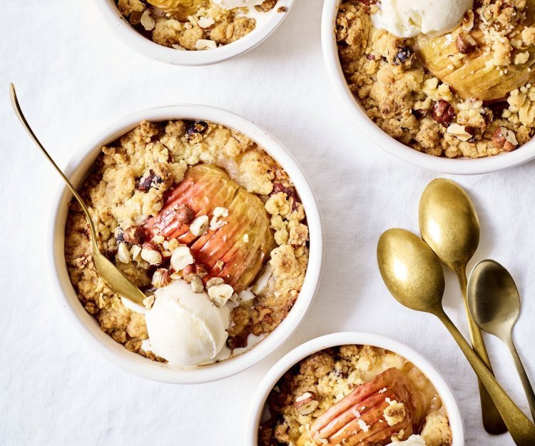 Feestelijke appelcrumble met nootjes en gember Van deze appelcrumble begin je spontaan te glimlachen van blijdschap. We dienen hem op in verschillende potjes met gouden lepeltjes en een bolletje vanilleijs recht van bij de boer.